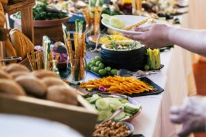 close up of people taking food from table at event party with catering self service | Blogs | Taste Of Bollywood Halal Indian Restaurant Adelaide